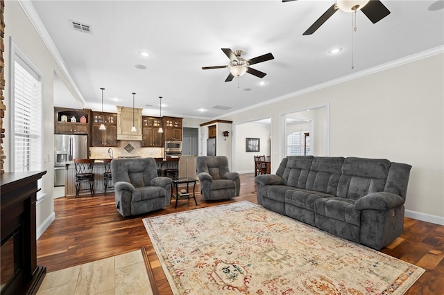 living room with visible vents, crown molding, baseboards, and dark wood-style flooring