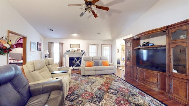 living area featuring visible vents, lofted ceiling, wood finished floors, and a fireplace