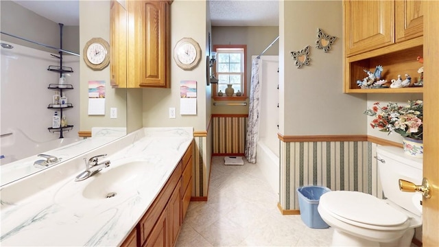 bathroom with baseboards, toilet, vanity, and shower / bath combination with curtain