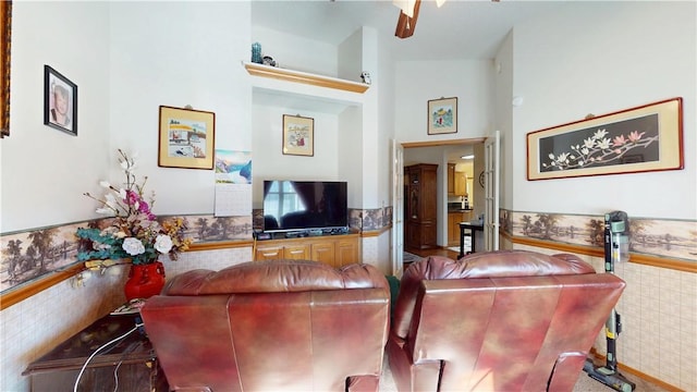 living area with a towering ceiling, wainscoting, and wallpapered walls