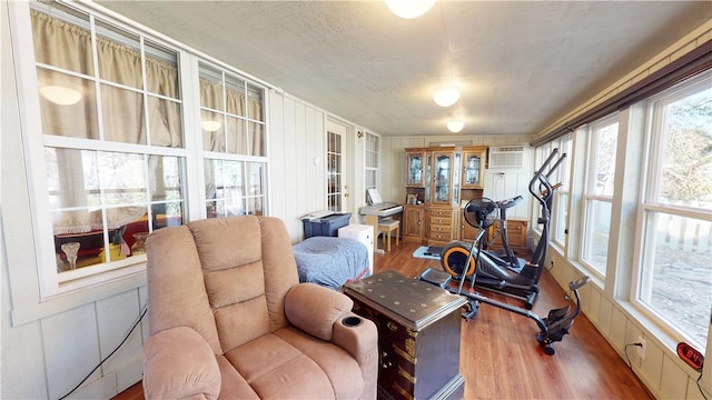 workout room with a wall unit AC and wood finished floors