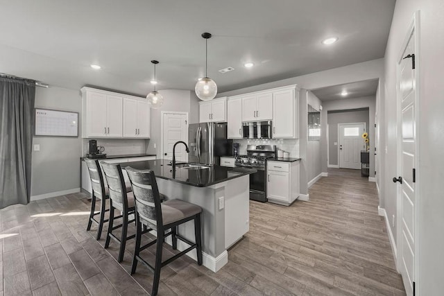 kitchen with a kitchen breakfast bar, dark countertops, appliances with stainless steel finishes, and light wood finished floors