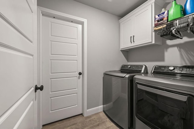clothes washing area featuring washer and dryer, wood finish floors, baseboards, and cabinet space