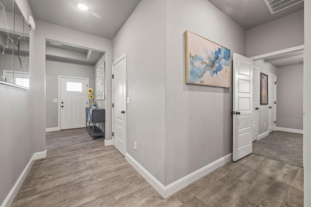 hall featuring visible vents, baseboards, and wood finished floors