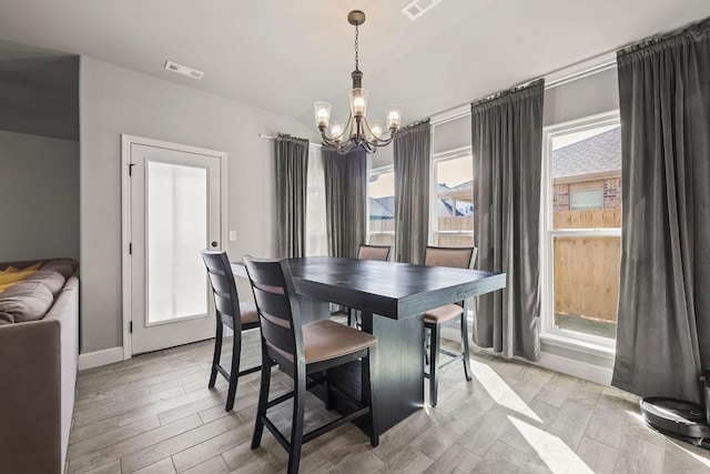 dining area with light wood-type flooring, an inviting chandelier, baseboards, and visible vents