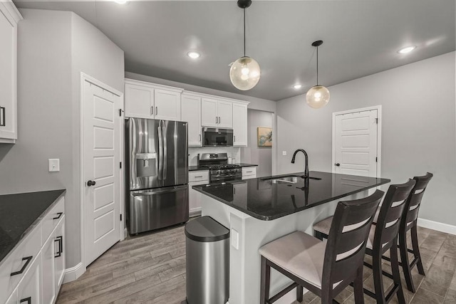 kitchen with white cabinetry, light wood-style floors, a kitchen bar, stainless steel appliances, and a sink