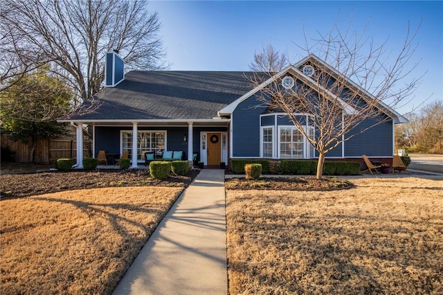 view of front of property featuring covered porch, a chimney, and fence