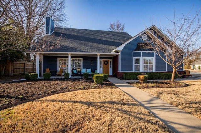 view of front of property featuring fence, roof with shingles, a porch, a chimney, and brick siding