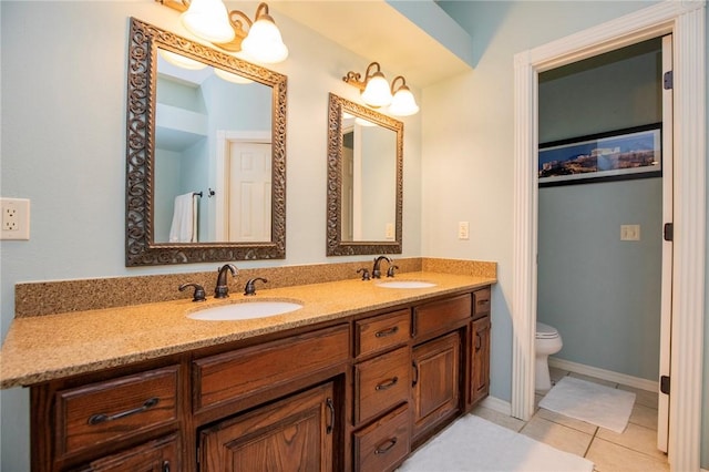 bathroom with a sink, toilet, double vanity, and tile patterned floors