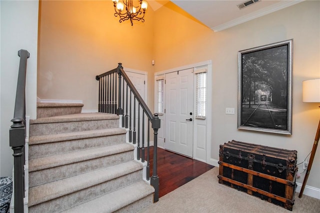 foyer with visible vents, baseboards, stairs, ornamental molding, and a notable chandelier