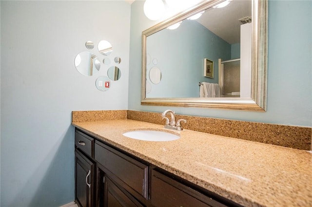 bathroom featuring vanity, visible vents, and a shower with door