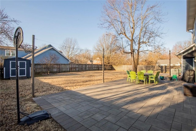 view of patio / terrace with a storage shed, outdoor dining area, a fenced backyard, and an outdoor structure