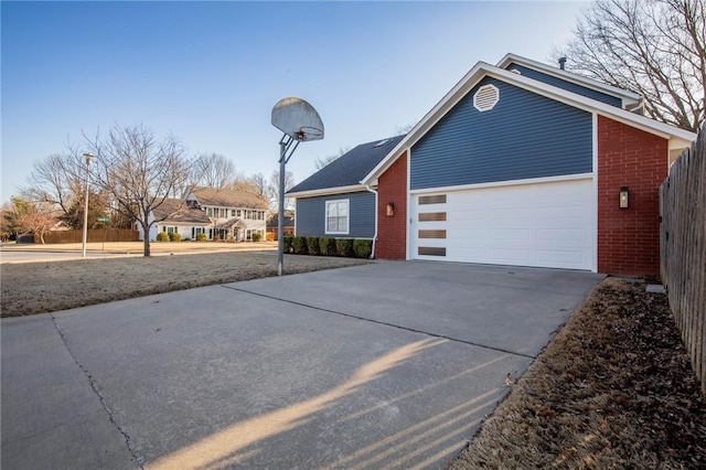 view of front of house with a garage, brick siding, concrete driveway, and fence