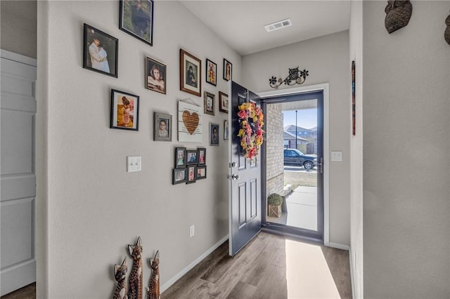 doorway featuring visible vents, baseboards, and wood finished floors