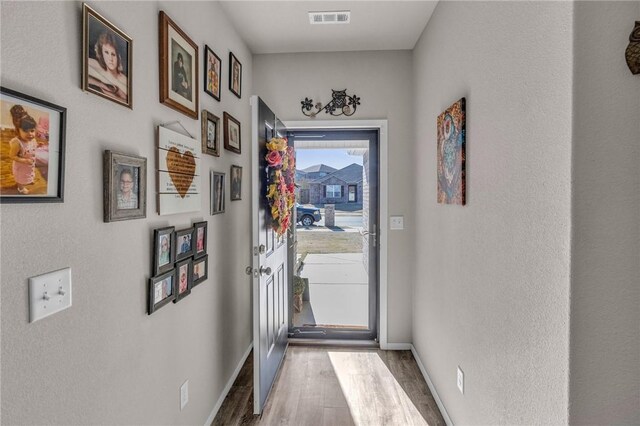 doorway featuring wood finished floors, visible vents, and baseboards