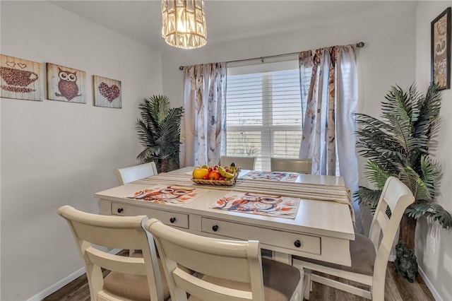 dining space with an inviting chandelier, wood finished floors, and baseboards