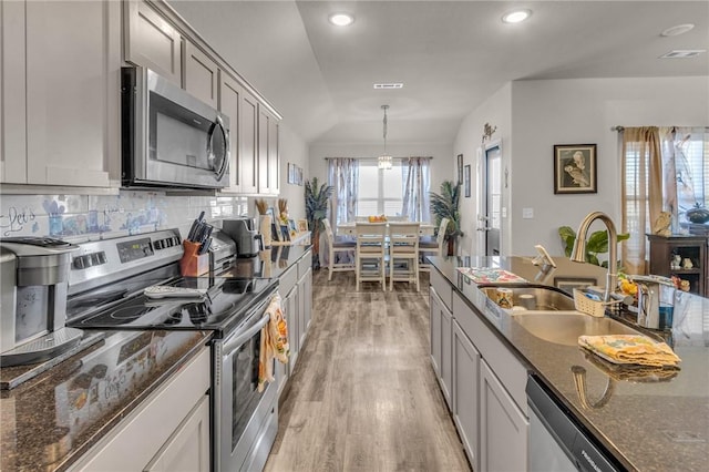 kitchen with visible vents, light wood-type flooring, decorative backsplash, stainless steel appliances, and a sink