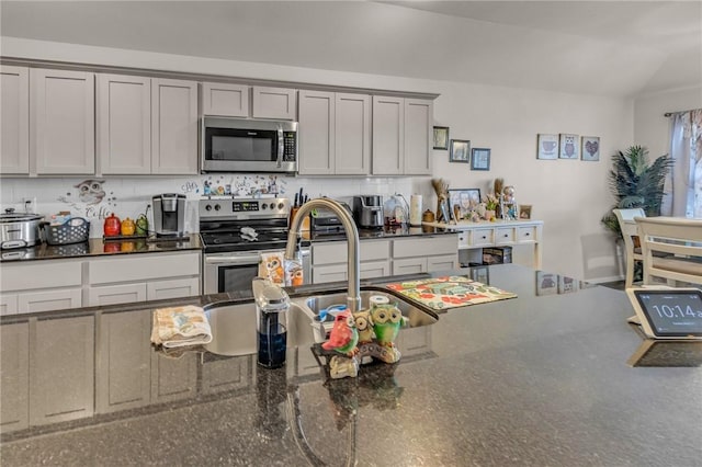 kitchen with tasteful backsplash, gray cabinets, appliances with stainless steel finishes, and dark stone counters