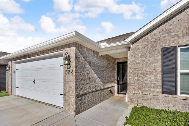 property entrance with brick siding, driveway, and a garage