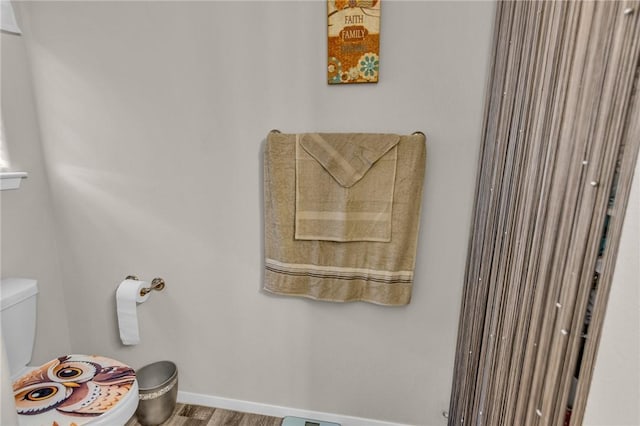 bathroom with baseboards, toilet, and wood finished floors