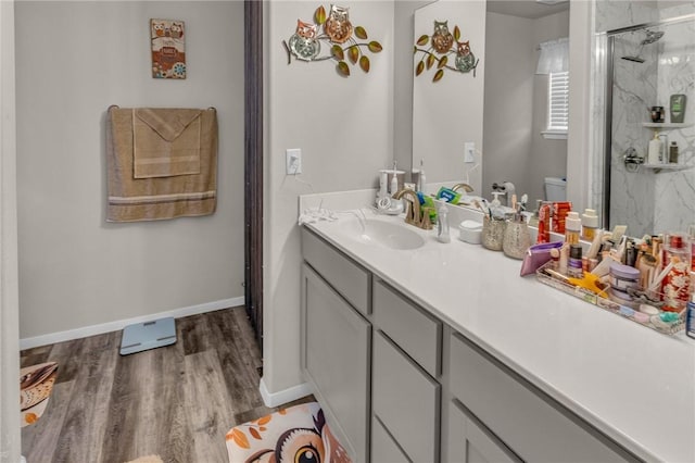 full bathroom featuring vanity, wood finished floors, baseboards, a marble finish shower, and toilet