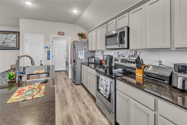 kitchen featuring backsplash, light wood finished floors, appliances with stainless steel finishes, and a sink