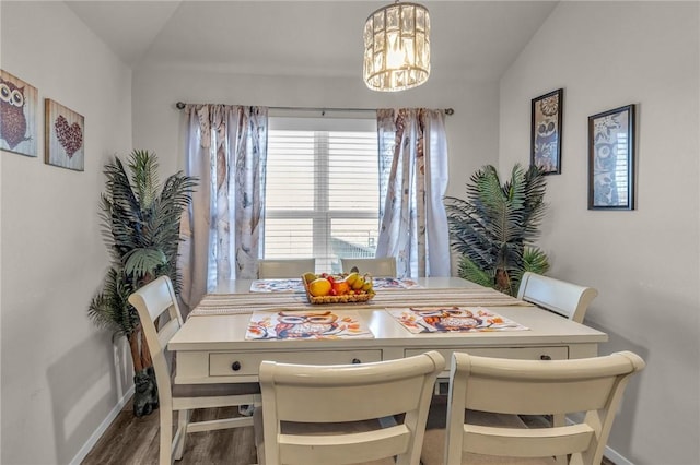 dining space featuring a notable chandelier, baseboards, lofted ceiling, and wood finished floors