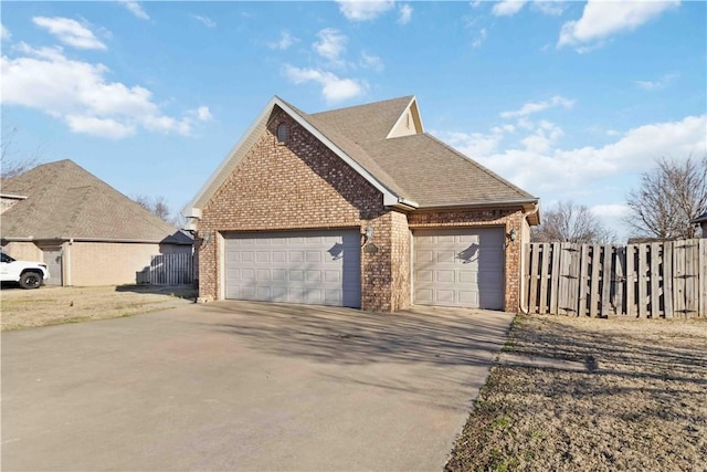 view of property exterior with fence, brick siding, driveway, and a shingled roof