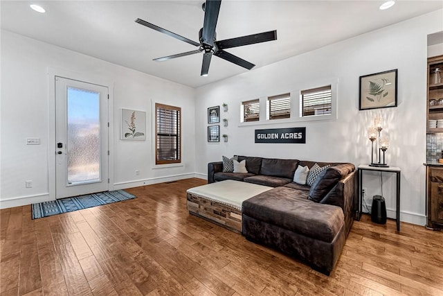 living room with recessed lighting, baseboards, and wood-type flooring