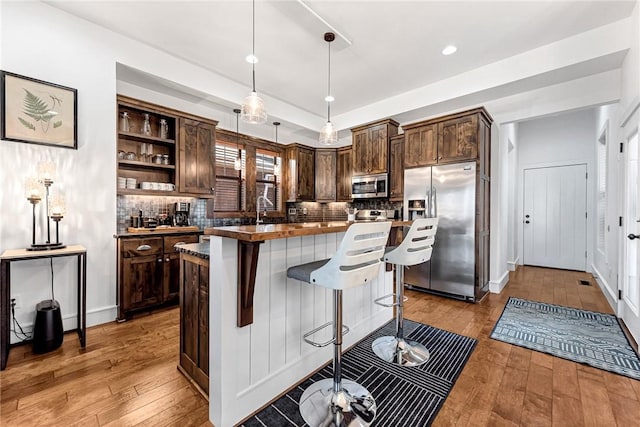 kitchen with light wood-type flooring, stainless steel appliances, dark brown cabinets, and a center island