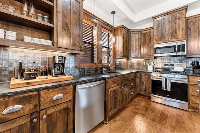 kitchen featuring a sink, decorative light fixtures, tasteful backsplash, hardwood / wood-style floors, and stainless steel appliances