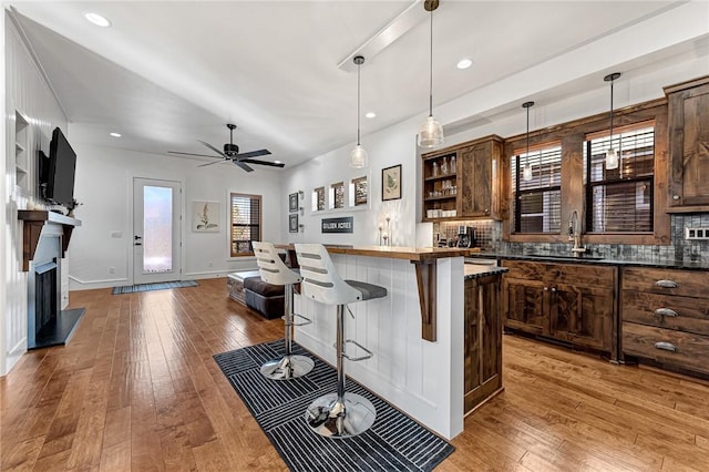 kitchen with a kitchen bar, backsplash, light wood finished floors, and a sink