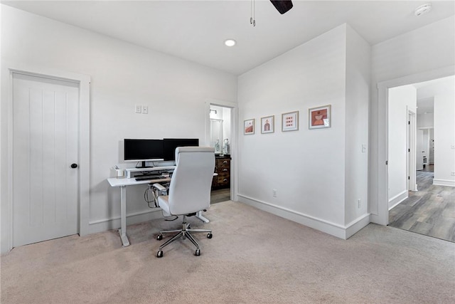 carpeted home office featuring a ceiling fan and baseboards