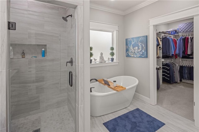 bathroom with a spacious closet, a shower stall, baseboards, a freestanding bath, and ornamental molding