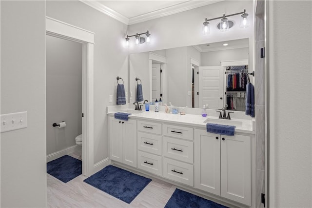 full bath with a sink, toilet, double vanity, and crown molding