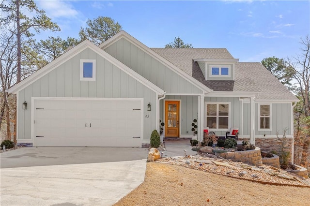 view of front of property with concrete driveway, an attached garage, board and batten siding, and a shingled roof