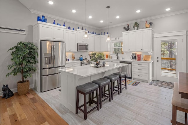 kitchen featuring a breakfast bar, stainless steel appliances, light countertops, white cabinets, and crown molding