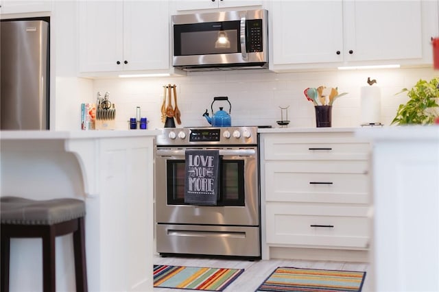 kitchen with decorative backsplash, appliances with stainless steel finishes, white cabinets, and light countertops