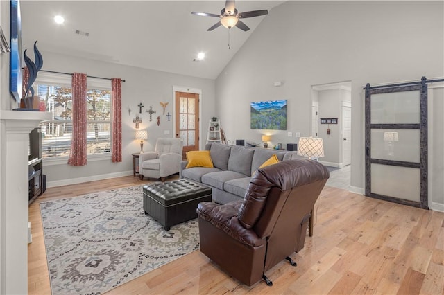 living area featuring a ceiling fan, light wood-style floors, and a barn door