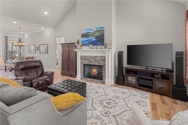 living room featuring wood finished floors, baseboards, high vaulted ceiling, a fireplace, and a notable chandelier