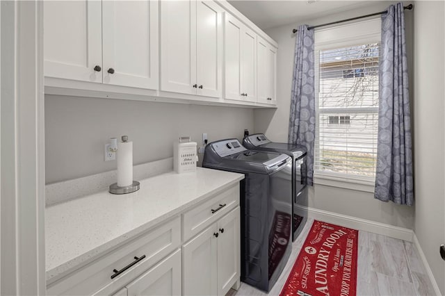 clothes washing area with washer and dryer, baseboards, cabinet space, and a wealth of natural light