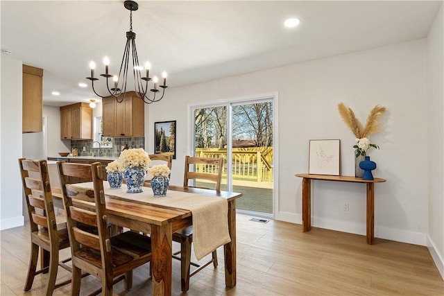 dining room featuring baseboards, visible vents, and light wood finished floors