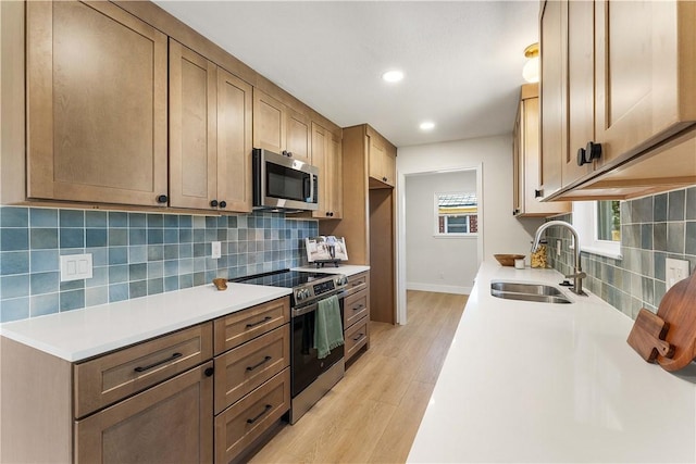 kitchen featuring a sink, light wood-style flooring, backsplash, and stainless steel appliances