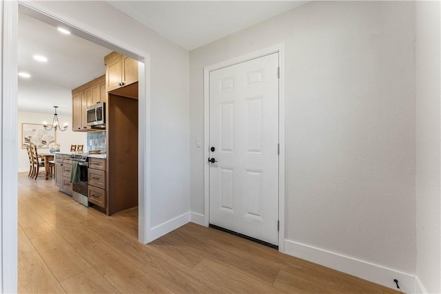 interior space featuring baseboards, a notable chandelier, and light wood finished floors