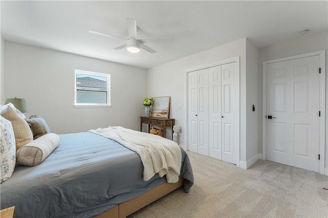 bedroom featuring baseboards, light colored carpet, a closet, and ceiling fan