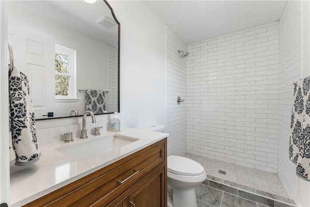 full bathroom featuring vanity, toilet, and tiled shower