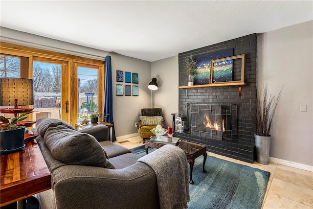 tiled living area featuring a brick fireplace and baseboards