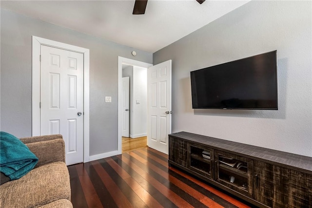 living room featuring baseboards, dark wood-style floors, and a ceiling fan