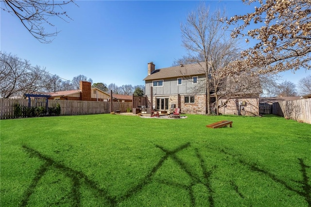 rear view of property featuring a patio area, a fenced backyard, a lawn, and a chimney