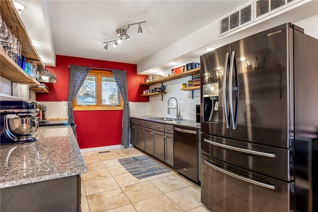 kitchen with visible vents, open shelves, a sink, dishwasher, and stainless steel fridge